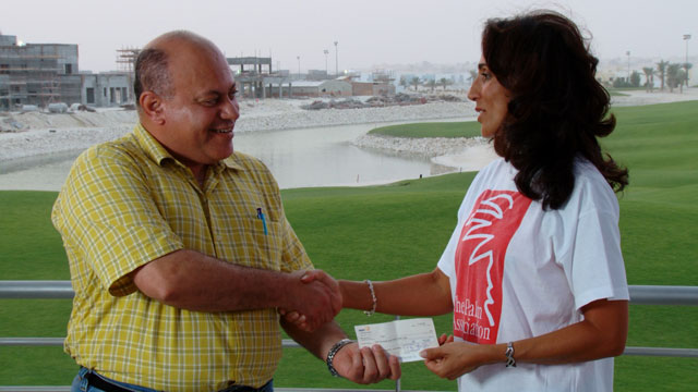 Mahmood Al-Yousif of Masadir Media presenting a cheque to Nadia Swan of The Palm Association
